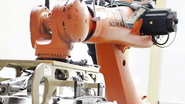 KUKA KR QUANTEC机器人将重型消音器运输到工作站。